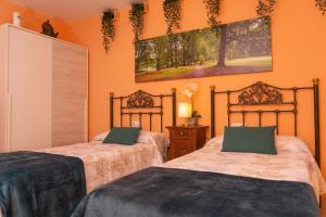 two beds in a room with orange walls at La Casita de Lucia in Trescasas