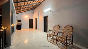 un pasillo con 2 sillas y una cocina en una casa en MALHAR MARARI HOMESTAY, en Mararikulam