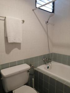 a bathroom with a toilet and a bath tub and a window at City Tropical Home I in George Town