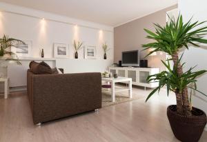 a living room with a couch and two palm trees at Meer Residenz Warnemuende in Warnemünde