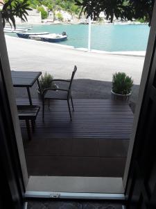 a wooden porch with a table and benches and the water at Holiday Home By The Sea - Nina & Kate in Ston