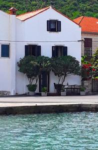 a white house with trees in front of the water at Holiday Home By The Sea - Nina & Kate in Ston