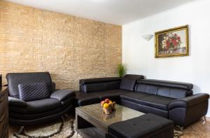 a living room with leather furniture and a brick wall at Holiday Home By The Sea - Nina & Kate in Ston