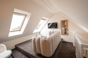 ein Wohnzimmer im Dachgeschoss mit einem Sofa und Fenstern in der Unterkunft Lifestylehotel Sand in Timmendorfer Strand