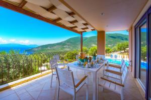 a white table and chairs on a balcony with a view at Villa Andromeda in Sivota