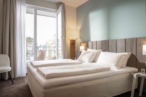 a large bed in a room with a large window at SAND Lifestylehotel in Timmendorfer Strand