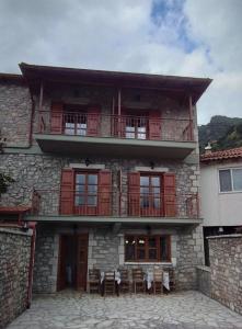 a building with a balcony with tables and chairs at Ξενώνας Ερυκίνη in Dhímitra +16 photos