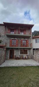 a large brick building with tables and chairs in front of it at Ξενώνας Ερυκίνη in Dhímitra