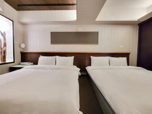 2 camas en una habitación de hotel con sábanas blancas en CHECK inn Express Taichung Fengchia, en Taichung