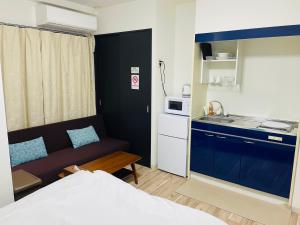 um pequeno quarto com um sofá e uma cozinha em ロイヤルハイツ桜川コンドミニアム em Osaka