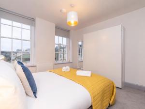 1 dormitorio con 1 cama blanca grande con manta amarilla en Pass the Keys Stunning 2 bed retreat in the heart of Bath, en Bath
