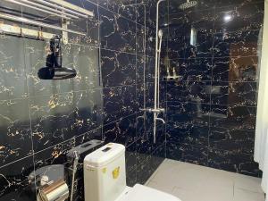 a black and gold bathroom with a toilet and a shower at Kim's Garden in Con Dao