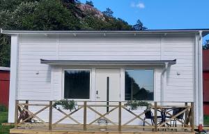 a small white shed with a wooden deck at Havsnära Stuga in Klövedal