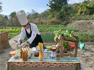 a chef preparing food on a table in a garden at Paatlidun Safari Lodge, Jim Corbett in Garjia