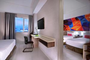 a hotel room with two beds and a television at favehotel Tanah Abang - Cideng in Jakarta