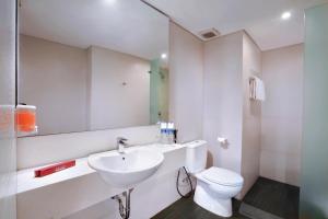 a bathroom with a sink and a toilet and a mirror at favehotel Tanah Abang - Cideng in Jakarta