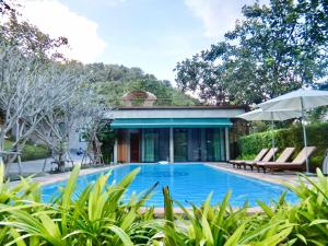 a house with a swimming pool and two chairs and an umbrella at The Height Khaoyai Resort in Ban Huai Sok Noi