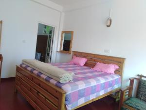 1 dormitorio con cama de madera y almohadas rosas en Forest Cyniciam Homestay, en Ohiya