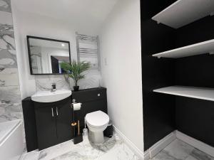 a bathroom with a sink and a toilet and a mirror at Modern 2 Bedroom Aesthetic Apt in Manchester