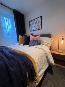 a bedroom with a bed with pillows and a window at Modern 2 Bedroom Aesthetic Apt in Manchester