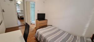 um pequeno quarto com uma cama e uma televisão em Luton, LU3 Double Ensuite room em Luton