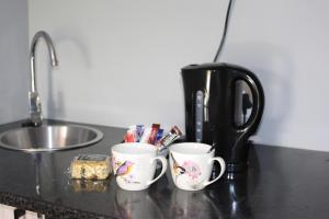 tres tazas de café sentadas en un mostrador junto a un fregadero en At the River Guest House en Kroonstad