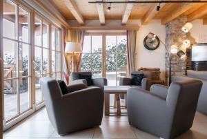 ein Wohnzimmer mit Stühlen, einem Tisch und Fenstern in der Unterkunft AvenidA Panorama Chalet by Alpin Rentals in Piesendorf