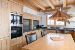 AvenidA Panorama Chalet by Alpin Rentals في بيسندورف: مطبخ مع طاولة خشبية مع كراسي وضوء مستنقع