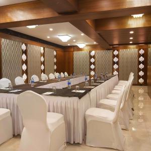 una gran sala de reuniones con una mesa larga y sillas blancas en Quality Inn Mint City Centre, en Pune