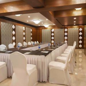 ein großer Besprechungsraum mit einem langen Tisch und weißen Stühlen in der Unterkunft Quality Inn Mint in Pune
