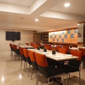 ein Restaurant mit Tischen und Stühlen und einem Flachbild-TV in der Unterkunft Quality Inn Mint City Centre in Pune