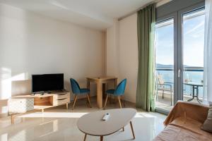 salon z telewizorem, stołem i krzesłami w obiekcie Georgia seaview apartment B3 w Kalamácie