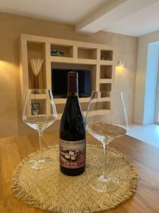 a bottle of wine and two glasses on a table at Suite cosy au cœur de Vinzelles proche Mâcon Tout équipé avec salon d'extérieur in Vinzelles
