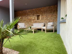 un patio con muebles blancos y césped verde en Suite cosy au cœur de Vinzelles proche Mâcon Tout équipé avec salon d'extérieur en Vinzelles