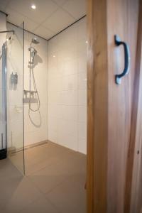 a bathroom with a shower with a glass door at Boutique Hotel Texel in De Cocksdorp