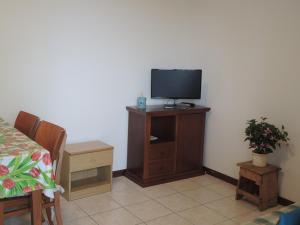 Habitación con TV en un soporte de madera con cama en Amazing apartment with terrace for 5 guests, en Bibione