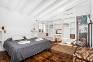 a white bedroom with a bed and a chair at Casa Esquinera - Villa en Trebaluger in Es Castell