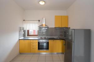 eine Küche mit gelben Schränken und einem Kühlschrank aus Edelstahl in der Unterkunft Apartman Roko in Umag