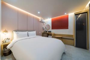 a bedroom with a large white bed and a bathroom at Browndot Hotel Namchuncheon in Chuncheon