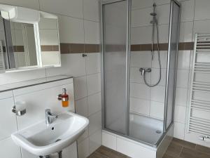 La salle de bains est pourvue d'un lavabo et d'une douche. dans l'établissement M&M Hotel - Neu Wulmstorf, à Neu Wulmstorf