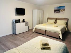 Cette chambre comprend deux lits et une télévision. dans l'établissement M&M Hotel - Neu Wulmstorf, à Neu Wulmstorf