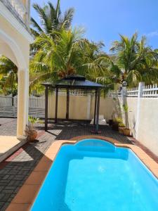 a swimming pool in a backyard with a table and palm trees at EHolidays Villa in Pereybere