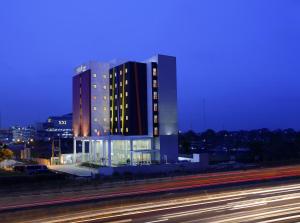 a large building with lights on in front of a highway at Amaris Hotel Bekasi Barat in Bekasi