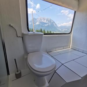 a bathroom with a toilet with a view of a mountain at Glampingbus Lindwurm in Irdning