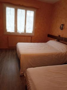 two beds in a room with two windows at La Cremaillere in Miremont