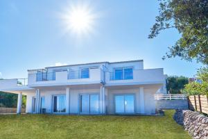 a white house with blue windows and a yard at Affittimoderni Isola Rossa Cala Serena - PASE02 in Cascabraga