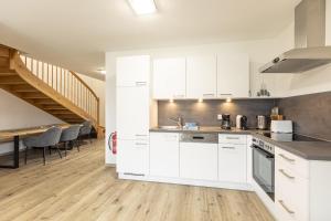 cocina con armarios blancos y comedor en Inzell Chalets by ALPS RESORTS en Inzell