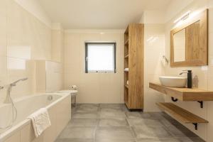 een witte badkamer met een bad en een wastafel bij Inzell Chalets by ALPS RESORTS in Inzell