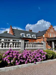 uma cerca branca com flores roxas em frente a um edifício em Villa Brunnby em Mölle