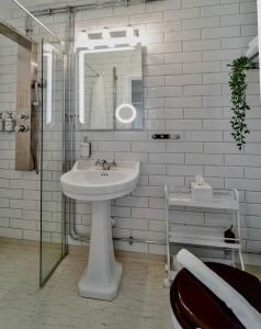 W białej łazience znajduje się umywalka i lustro. w obiekcie Villa Brunnby w mieście Mölle